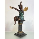 A patinated and parcel-gilt bronze figure of a fairy, modelled in silver cap, seated on a column