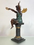 A patinated and parcel-gilt bronze figure of a fairy, modelled in silver cap, seated on a column