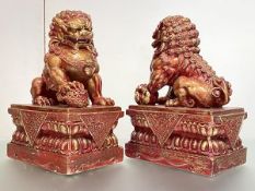 A pair of large composition models of Chinese Buddhistic lions, decorated in red and gilt, each in