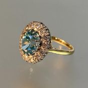 A blue zircon and diamond cluster ring, the oval-cut zircon claw-set within a band of sixteen