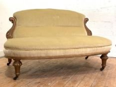 A late Victorian walnut-framed boudoir settee, the back with acanthus-carved "S" scroll terminals,