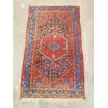 A hand-knotted Iranian Hamadan rug, the red field with lozenge medallion and all-over geometric