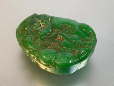 A Chinese carved jadeite pendant, of shaped oval form, modelled with scrolls, discs and other forms,