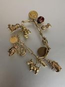 A 14ct gold chainlink charm bracelet suspending a quantity of 9ct and yellow metal charms, the chain