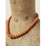 A single strand coral bead necklace, c. 1920, the graduated beads on a yellow metal box clasp.