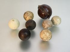 A group of six moulded gutta percha golf balls, one marked "Warwick", another "Dunlop" a third "