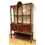 A fine Edwardian mahogany display cabinet, the projecting cornice over two glazed doors centred by a
