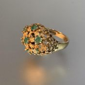A 1970's emerald dress ring, the domed textured basketweave plaque set with seven emerald points, on