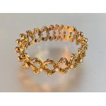 A 9ct gold articulated bracelet, of open fancy links, set to one side with seed pearls, stamped