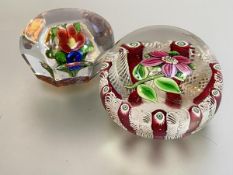 Two lampwork flower paperweights: the first, faceted, with a floral bouquet against an orange