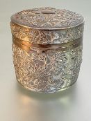 A Japanese white metal box, c. 1900, of cylindrical form, with lift-off domed cover, repousse