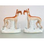 A large pair of Staffordshire flatback models of greyhounds, each modelled standing with a hare in