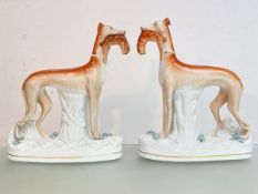 A large pair of Staffordshire flatback models of greyhounds, each modelled standing with a hare in
