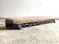 A Victorian walnut framed fender footstool, the upholstered top over pierced and floral carved