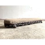 A Victorian walnut framed fender footstool, the upholstered top over pierced and floral carved