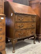 A mid 20th century figured walnut bow front bureau, the cross banded fall front revealing fitted