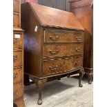 A mid 20th century figured walnut bow front bureau, the cross banded fall front revealing fitted