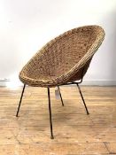 A vintage mid century wicker cone chair, raised on a black painted wirework frame, in the manner