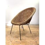 A vintage mid century wicker cone chair, raised on a black painted wirework frame, in the manner