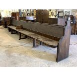 A large Victorian stained pine pew, with panelled back and seat, raised on shaped panel end supports
