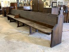 A large Victorian stained pine pew, with panelled back and seat, raised on shaped panel end supports