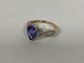 A 9ct gold dress ring set pear shaped blue/purple stone surrounded by diamond points and two pierced