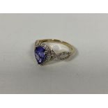 A 9ct gold dress ring set pear shaped blue/purple stone surrounded by diamond points and two pierced