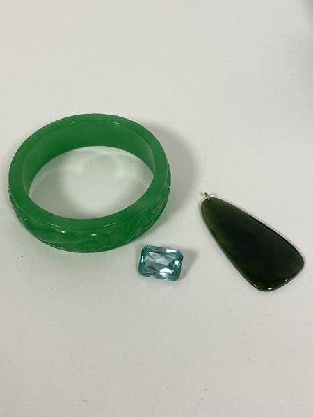 A carved green stone bangle with foliate carved decoration (7cm) and a spinach green stone pendant