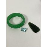 A carved green stone bangle with foliate carved decoration (7cm) and a spinach green stone pendant