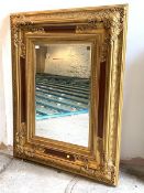 A Large gilt framed wall hanging mirror, the floral moulded frame enclosing a bevelled plate,