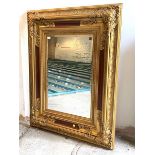 A Large gilt framed wall hanging mirror, the floral moulded frame enclosing a bevelled plate,