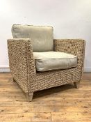 A wicker veranda chair of square form, with upholstered squab cushions, raised on square tapered
