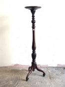 A Georgian style mahogany torchere, the circular dished top over turned and leaf carved column