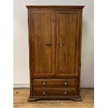 A hardwood double wardrobe, the twin panelled doors enclosing interior fitted for hanging, with