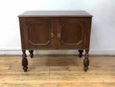 An early 20th century oak side cabinet, the moulded rectangular top over over two panelled doors,