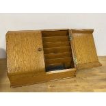 A 1930s/40s oak stationery box, the slope front with two doors and fitted interior (24cm x 36cm x