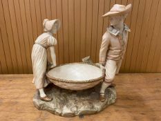 A Royal Worcester figural group of man and woman in hats carrying large basket, chips to gentleman's