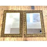 A Pair of gilt framed wall hanging mirrors, the floral moulded frames enclosing bevelled glass, 87cm