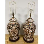 A pair of Imari vases of baluster form with lids later adapted to lamps on wooden bases some loss to