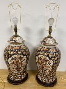 A pair of Imari vases of baluster form with lids later adapted to lamps on wooden bases some loss to