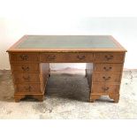 A reproduction yew wood twin pedestal desk, the top with inset tooled green leather writing