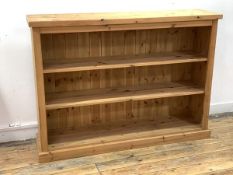 A pine floor standing bookcase, with two adjustable shelves, raised on a plinth base, W134cm, H97cm,