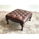 A footstool, upholstered in buttoned and studded oxblood leather, raised on cabriole supports,