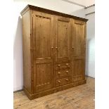A Pine triple wardrobe, with centre hanging cupboard and three drawers, flanked by two cupboards, on