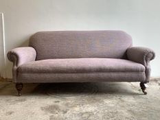 A Victorian three seat sofa, upholstered in a mottled lilac fabric, raised on turned walnut front