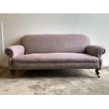 A Victorian three seat sofa, upholstered in a mottled lilac fabric, raised on turned walnut front