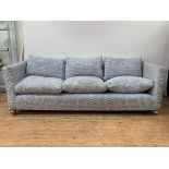 A contemporary three seat sofa, upholstered in a patterned blue and white cotton, with loose