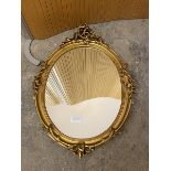 A rococo style oval wall mirror in gilt composition frame (68cm x 48cm)