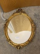 A rococo style oval wall mirror in gilt composition frame (68cm x 48cm)