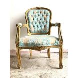 An early 20th century gilt framed fauteuil, the floral carved crest rail over shield back, fluted